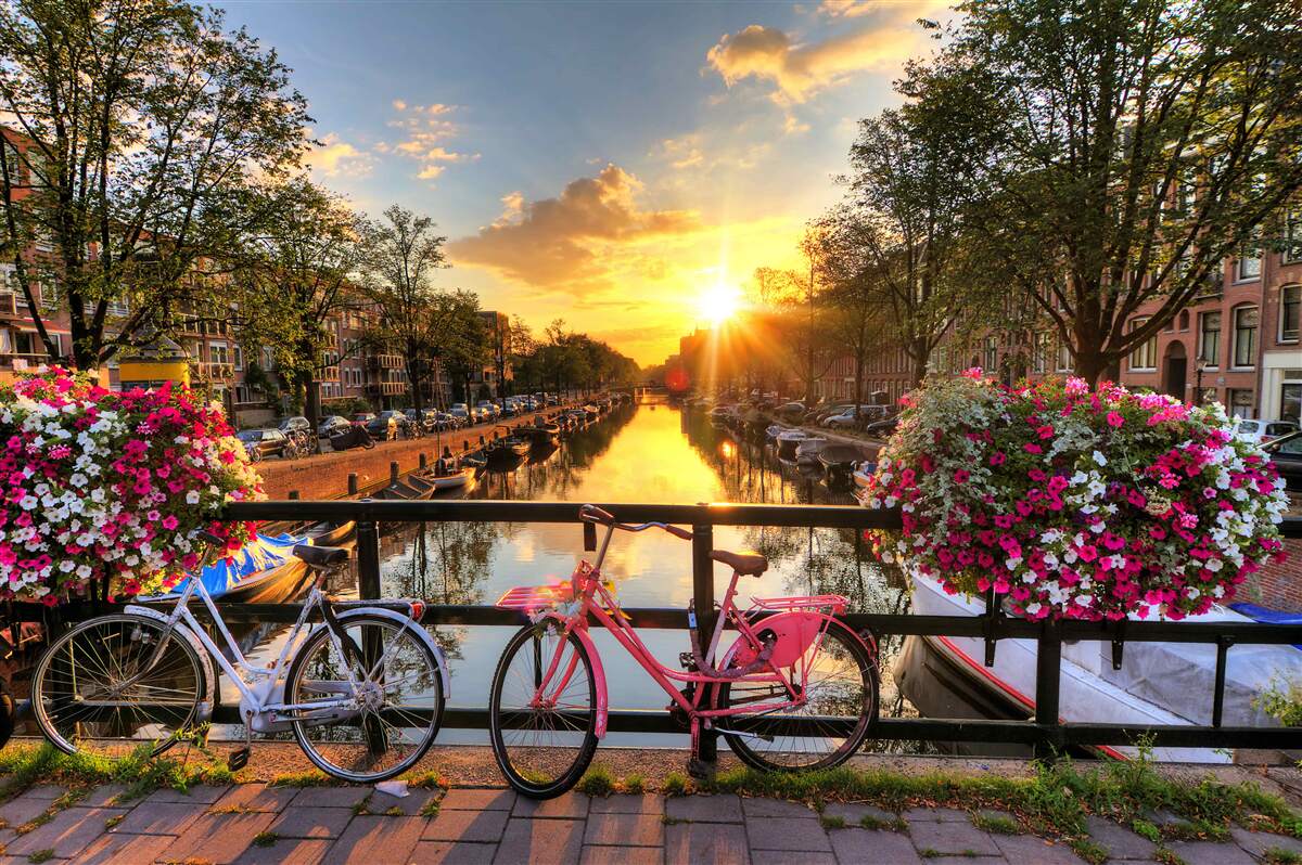 Papier peint coucher de soleil à amsterdam avec des vélos en arrière-plan