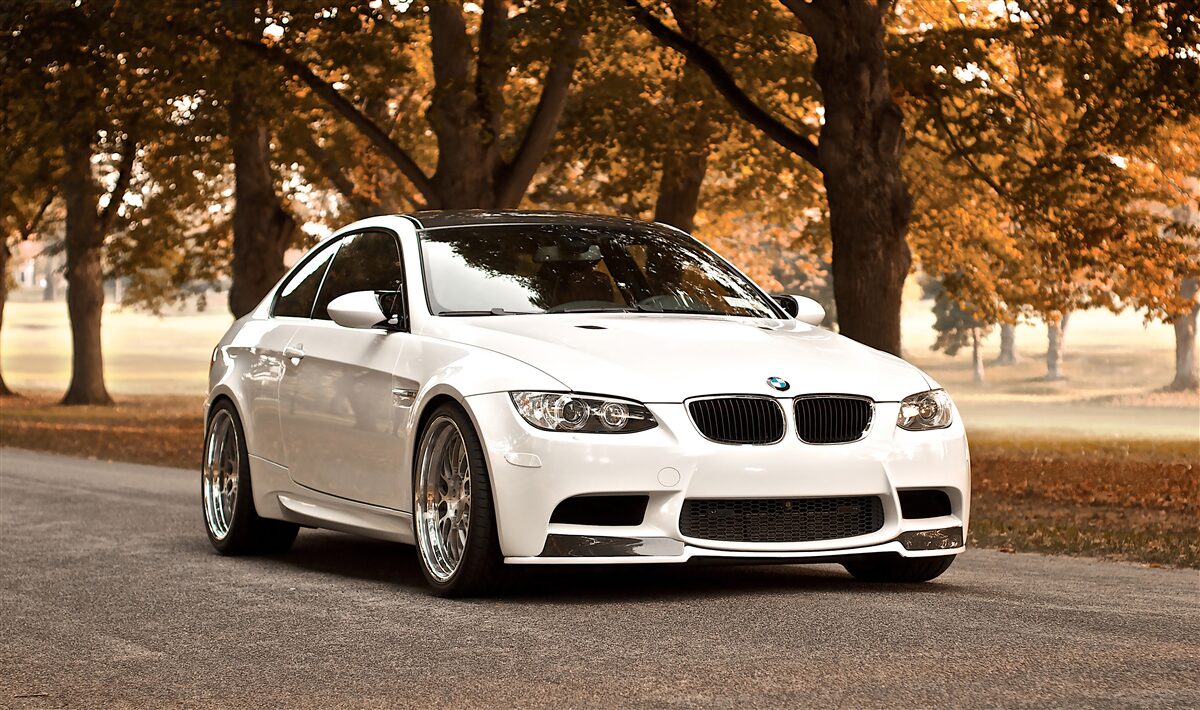 Papier peint une bmw blanche roule sur la route en automne